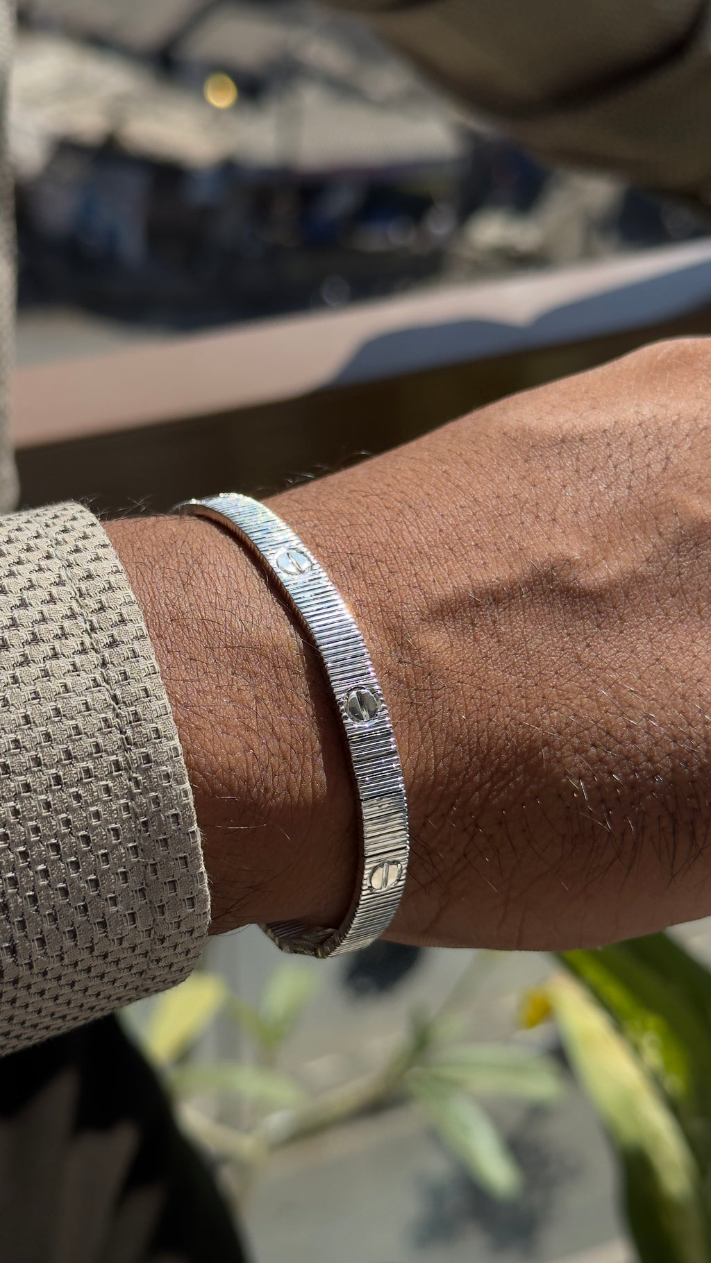 Silver bracelet on a wrist with a blurred background