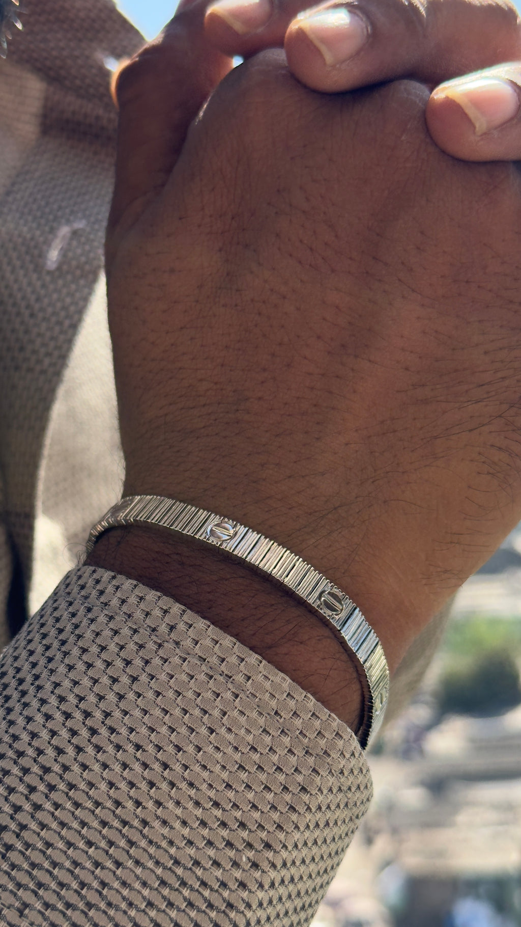 Close-up of a wrist wearing a silver bracelet with a blurred background