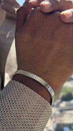Close-up of a wrist wearing a silver bracelet with a blurred background