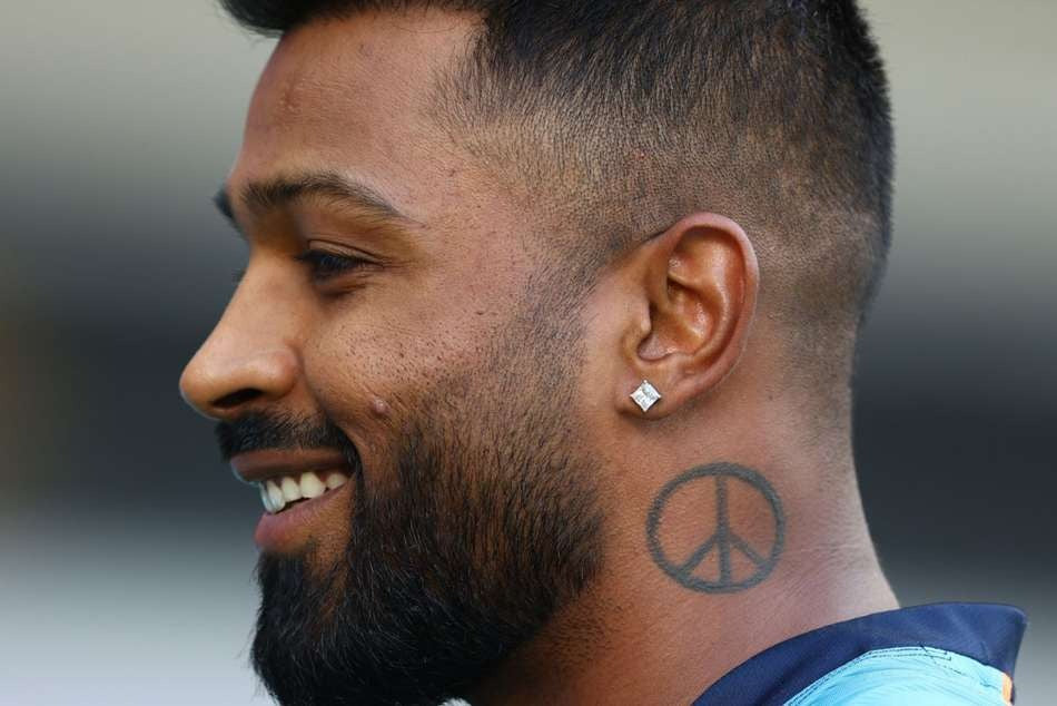 HARDIK PANDAY with a beard and peace sign tattoo on his neck, wearing a blue shirt.