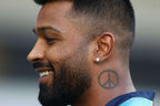 HARDIK PANDAY with a beard and peace sign tattoo on his neck, wearing a blue shirt.